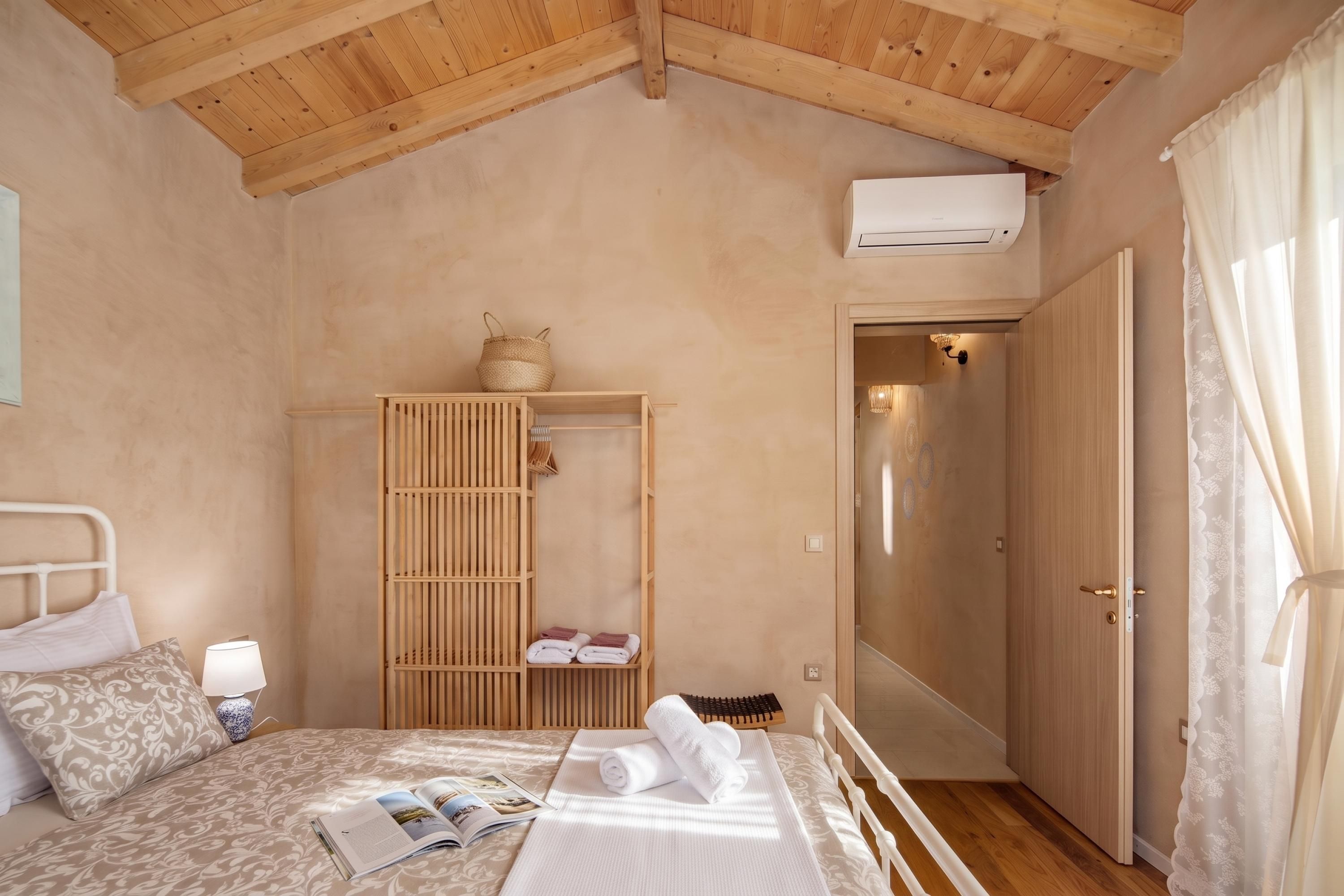 Une chambre à coucher avec un lit, une table de chevet, une lampe, une armoire en bois et une porte.