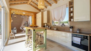 Una cocina moderna con vigas de madera, un ventanal grande y una zona de comedor con mesa y sillas.