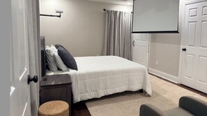 A bedroom with a bed, a ceiling fan, a projector screen, a door, and a small stool. - 3BR House 5 Minutes from Downtown Atlanta near Mercedes Benz Stadium World Cup (Decatur)