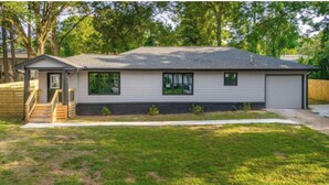 A single-story house with a front porch, a garage, and a small front yard. - 3BR House 5 Minutes from Downtown Atlanta near Mercedes Benz Stadium World Cup (Decatur)