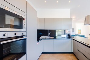 A modern kitchen with a built-in oven, microwave, and a large island with a sink. - Dar Sara Holiday Gozitan Home, IR-RABAT, Malta (IR-RABAT)