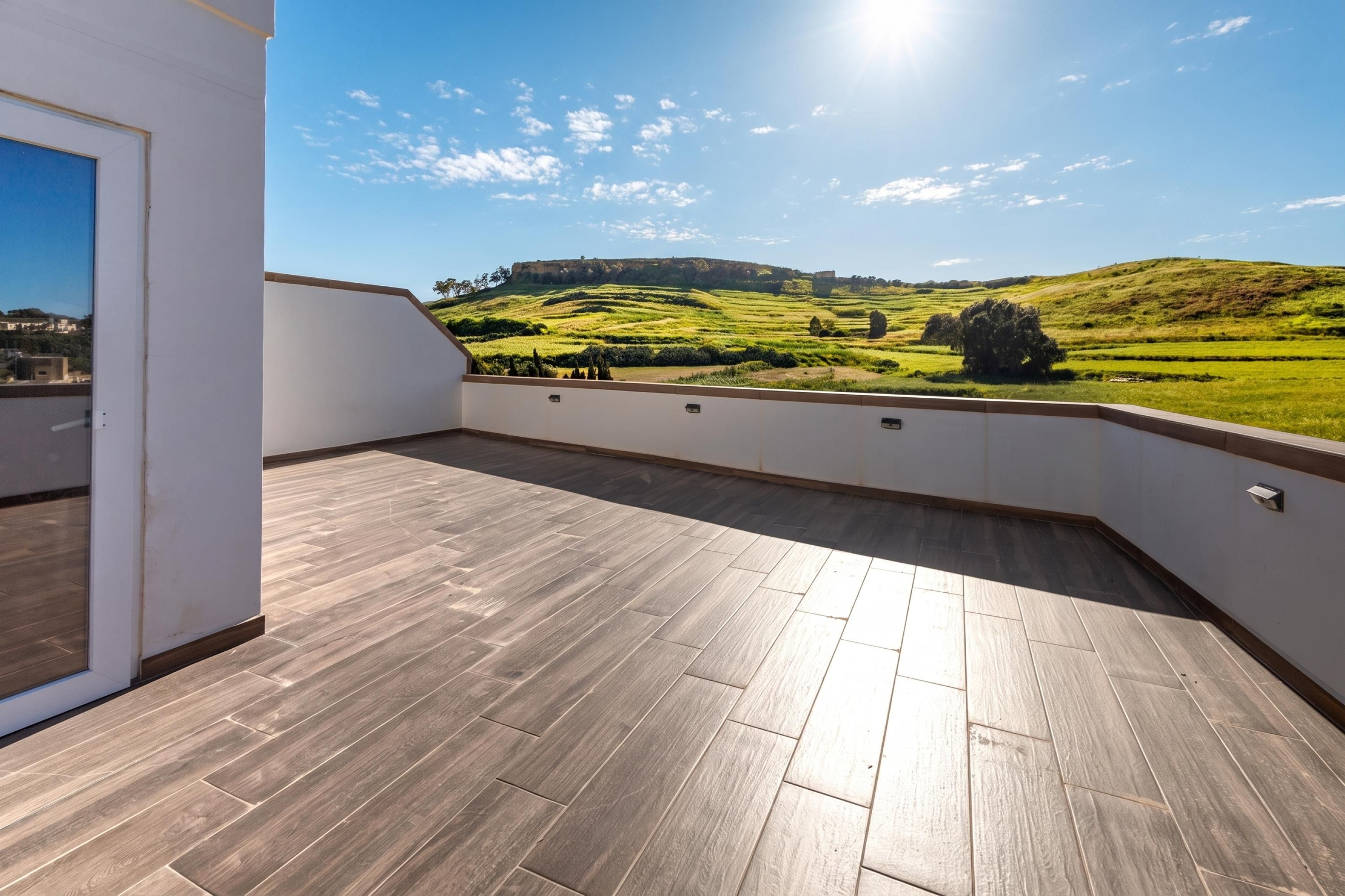 A balcony with a view of a green landscape and a hill.