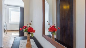 A hallway with a mirror, a vase with red flowers, and a door. - Rural Apt Lea for 2 /w Terrace, Šmarje, Slovenia (Šmarje)