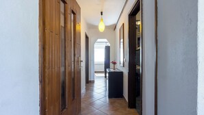 A hallway with wooden doors, a tiled floor, a hanging light fixture, and a small table with a vase. - Rural Apt Lea for 2 /w Terrace, Šmarje, Slovenia (Šmarje)
