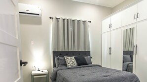 Une chambre à coucher comprenant un lit, une table de chevet, une armoire et un miroir.