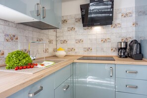 Cocina moderna con armarios azul claro, encimera de madera, pileta de acero inoxidable y cafetera.