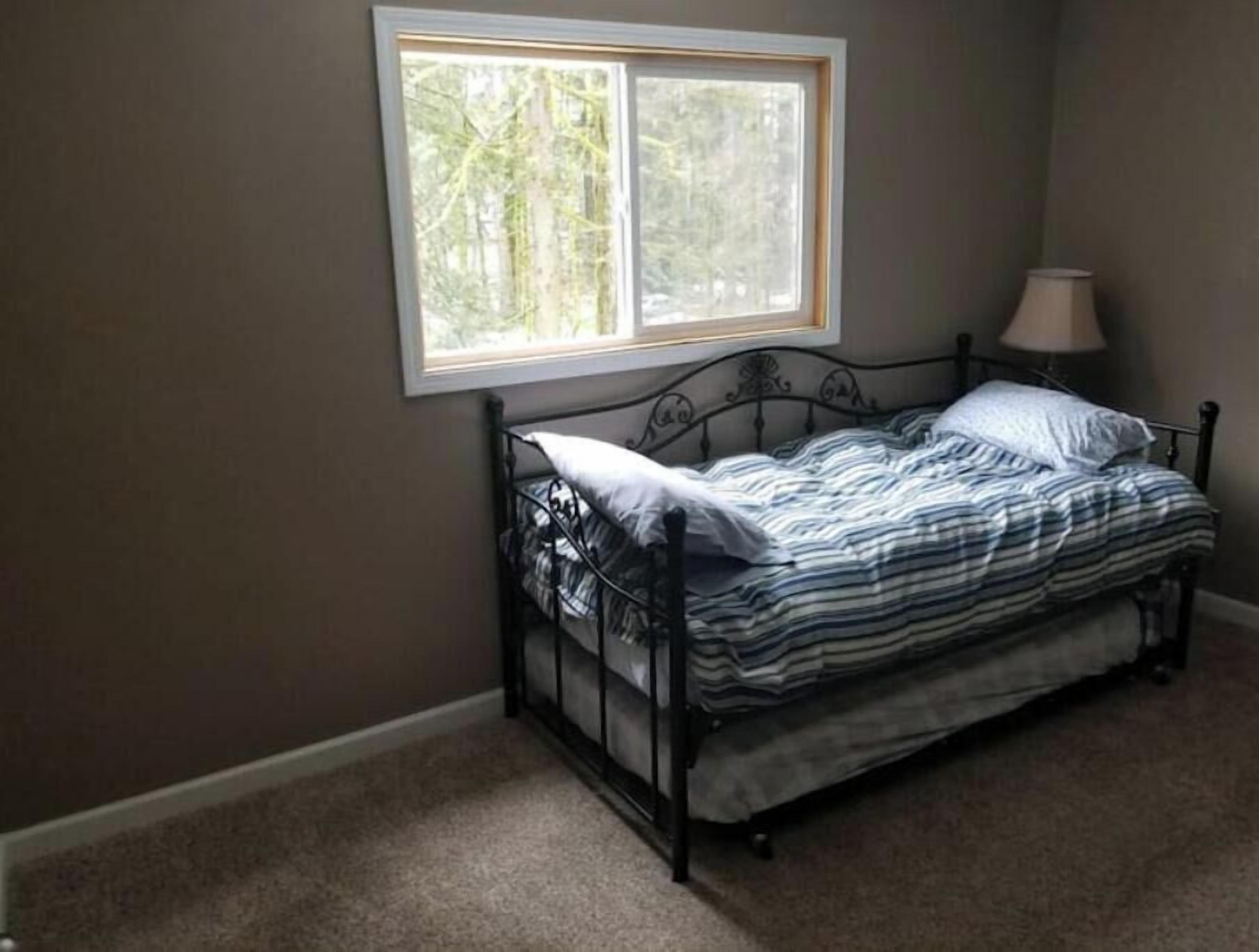 A bedroom with a single bed, a window, and a lamp.