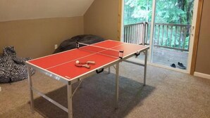Tafeltennistafel in een kamer met uitzicht op een balkon en terras.