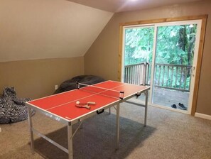 A ping pong table in a room with a view of a balcony and outdoor area. - Charming 4-bedroom cabin with AC in peaceful Rhododendron (Rhododendron)