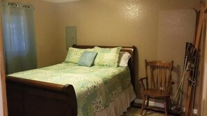 Een slaapkamer met een bed, een stoel en een deur.