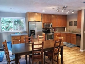 A kitchen with wooden cabinets, stainless steel appliances, and a dining table with chairs. - Charming 4-bedroom cabin with AC in peaceful Rhododendron (Rhododendron)