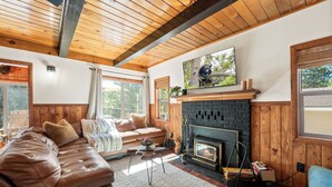 Un salon chaleureux avec une cheminée, un plafond en bois et un canapé confortable.