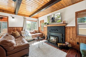 Ein gemütliches Wohnzimmer mit Kamin, Holzboden und einer bequemen Couch.