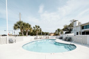 Ein Pool mit Liegestühlen und Palmen.