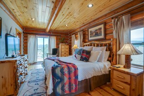 A log cabin bedroom with a bed, dresser, lamp, and a television. - Spacious lodge with stunning Moreno Valley views (Angel Fire)