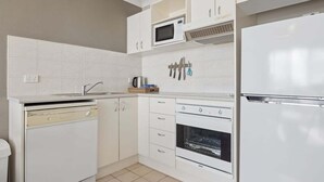 A modern kitchen with white cabinetry, a microwave, a stove, and a dishwasher. - Horizons 302 - Centrally located in town with pool access, tennis courts and undercover car parking (Jindabyne)