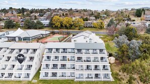 A multi-story hotel with a modern design, featuring balconies and a sports court. - Horizons 302 - Centrally located in town with pool access, tennis courts and undercover car parking (Jindabyne)