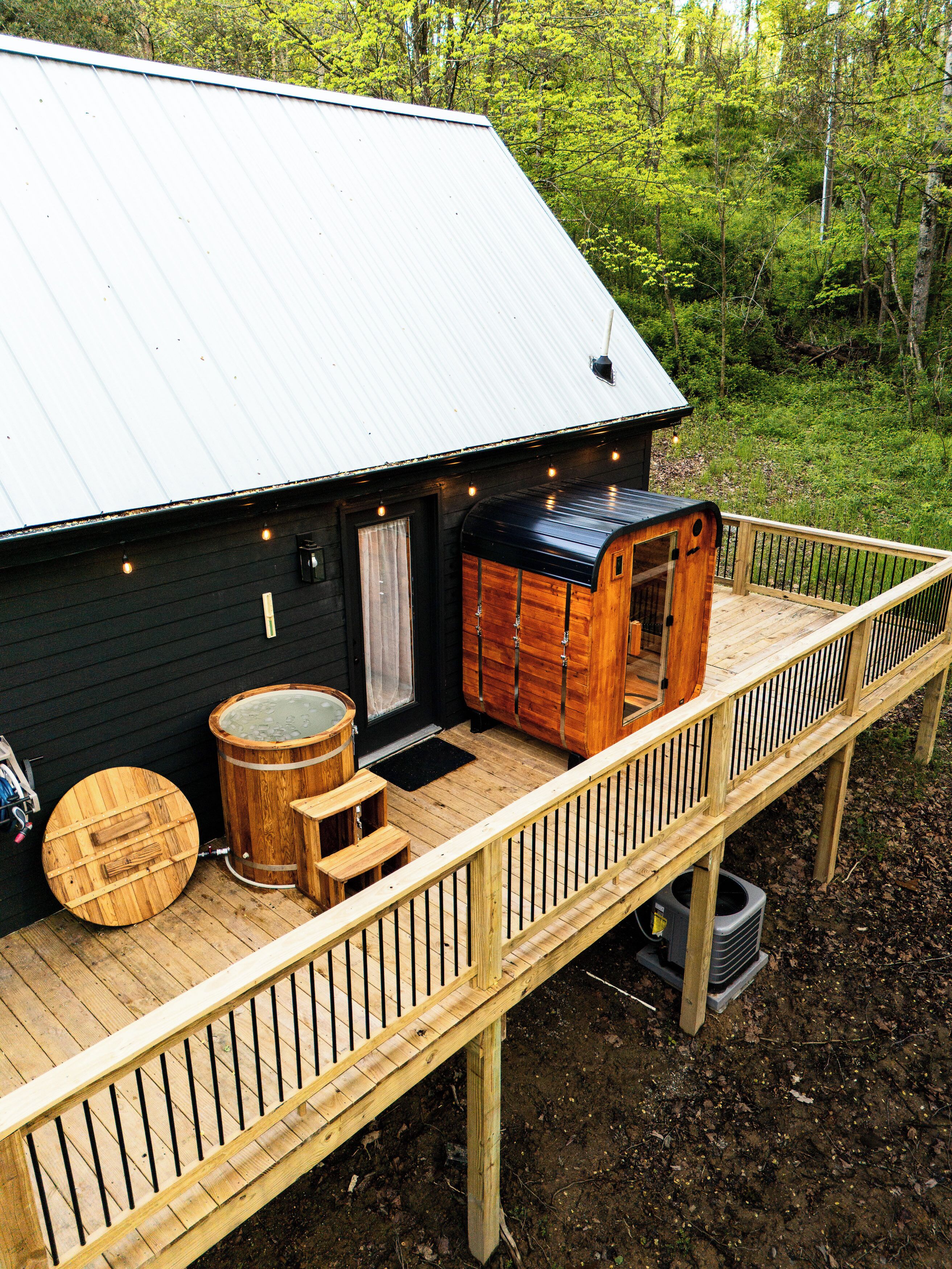 A cabin with a deck, a hot tub, and a wooden barrel.