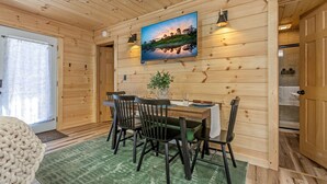 Een houten interieur met een eettafel, stoelen, een potplant en een televisie aan de muur.