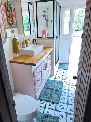 A bathroom with a white sink, wooden countertop, and patterned floor tiles.
