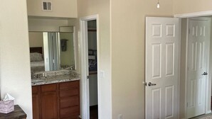 A bedroom with a bed, a dresser, a walk-in closet, and a bathroom with a mirror.