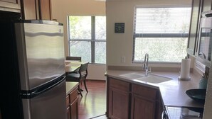 A kitchen with a refrigerator, stove, sink, and window.