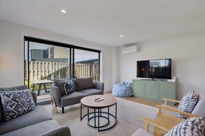 A modern living room with a sofa, armchair, coffee table, and a television on a cabinet.