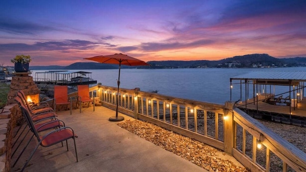 Une terrasse au bord de l’eau, avec une plateforme en bois, des sièges d’extérieur et une vue sur l’eau.