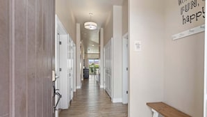 A hallway with a wooden floor, white doors, a bench, and a ceiling light fixture. - Estancia Resort Unit #404 (Saint George)