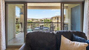 A balcony with a sofa, a table with chairs, and a view of a residential area. - Estancia Resort Unit #404 (Saint George)