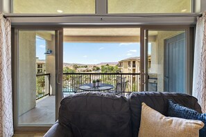 Ein Balkon mit einer Couch, einem Tisch mit Stühlen und Blick auf ein Wohngebiet.
