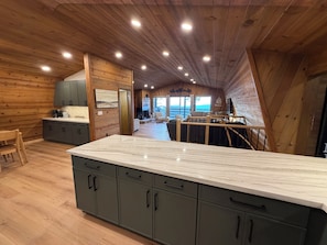 A modern kitchen with wooden walls, a marble countertop, and a view of the outdoors. - Shaver Lake Cabin, Views, 5 Acres, Sleeps 14, A/C, Starlink Wifi (Shaver Lake)
