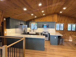 A modern kitchen with wooden ceiling, stainless steel appliances, and a large island. - Shaver Lake Cabin, Views, 5 Acres, Sleeps 14, A/C, Starlink Wifi (Shaver Lake)
