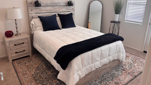 A bedroom with a bed, bedside table, lamp, mirror, and a potted plant. - Your Indio retreat awaits you (Indio)