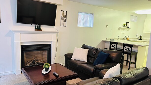 A living room with a fireplace, a television, a couch, and a small dining area.