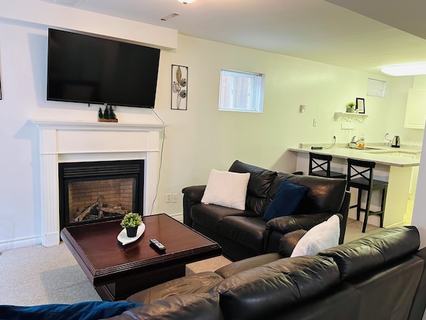 A living room with a fireplace, a television, a couch, and a small dining area.