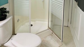 A bathroom with a glass-enclosed shower, a toilet, and a sink.