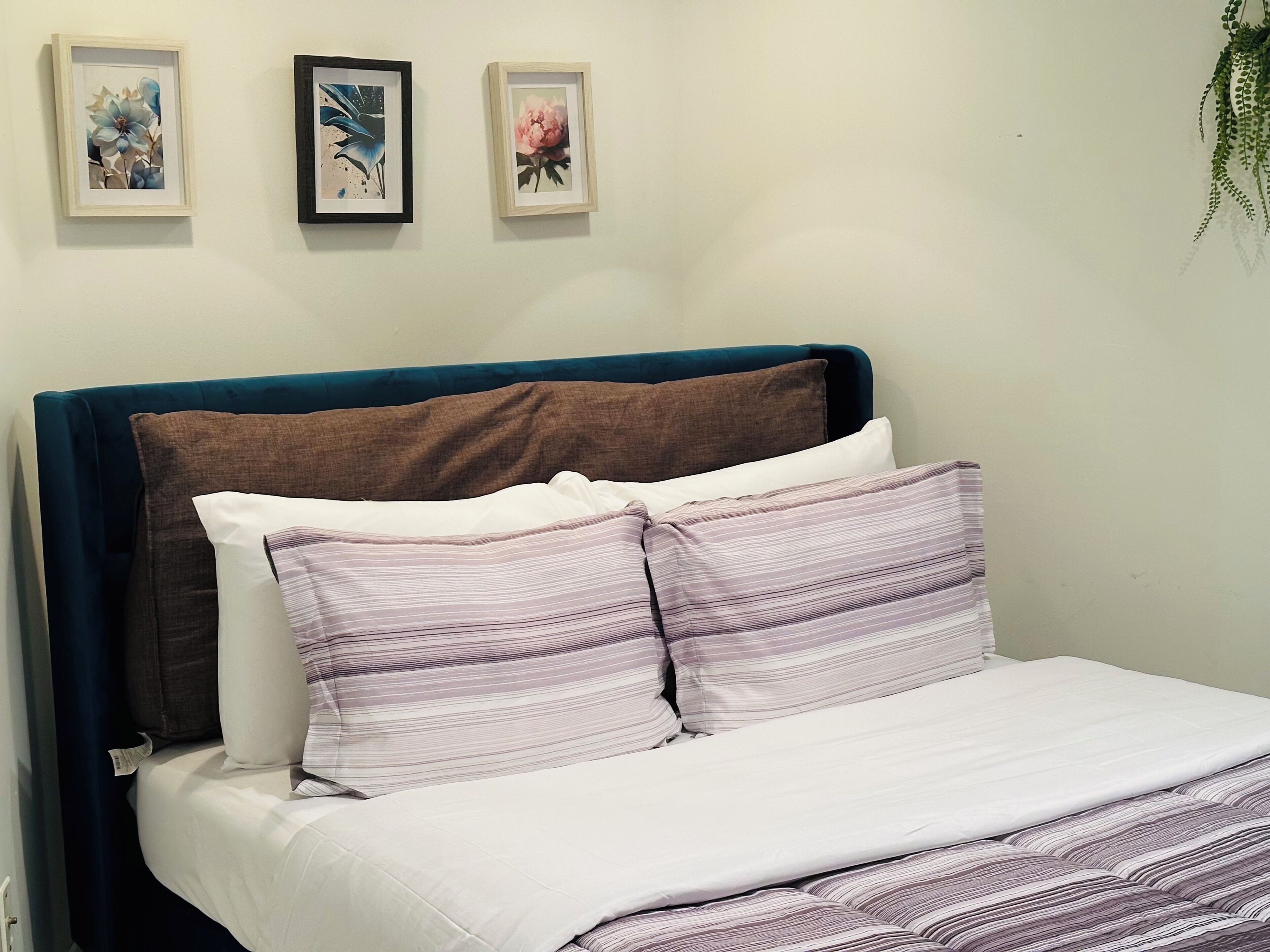 Ein Bett mit blauem Kopfteil, zwei Kissen und einer weißen Tagesdecke.