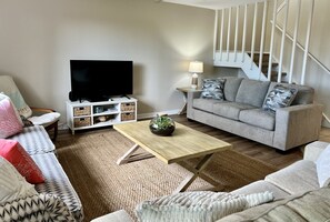 Ein Wohnzimmer mit einer Couch, einem Fernseher und einer Treppe.