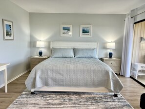 Ein Schlafzimmer mit einem Bett, zwei Nachttischen, einem Beistelltisch, einem Sessel und zwei gerahmten Bildern an der Wand.