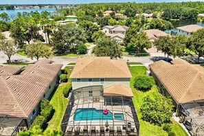 A residential area with houses, a swimming pool, and a lake in the background. - Spacious 6-bedroom house, Heated Pool, Hot Tub, Theater and Game Room! (Kissimmee)