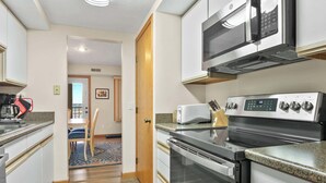 Eine Küche mit Mikrowelle, Toaster, Herd und Backofen. Ein Essbereich mit Stühlen und Tisch ist ebenfalls vorhanden.
