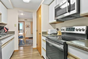 Eine Küche mit Mikrowelle, Toaster, Herd und Backofen. Ein Essbereich mit Stühlen und Tisch ist ebenfalls vorhanden.
