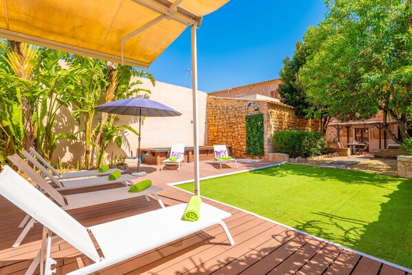 A poolside area with lounge chairs, a table, and a stone wall. - BONITO MEDITERRANEO - Charming village house with private pool and free Wi-Fi (Santanyí)