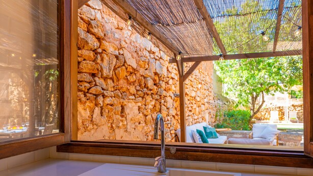 Ein Badezimmer mit einer Steinwand, einem Waschbecken und einem Fenster mit Blick auf einen Garten.