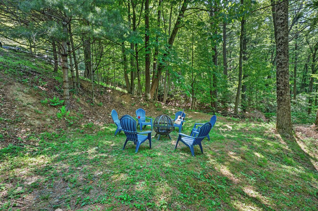 Un espace boisé doté d’un coin salon extérieur comprenant des chaises et une table, le tout entouré d’arbres.