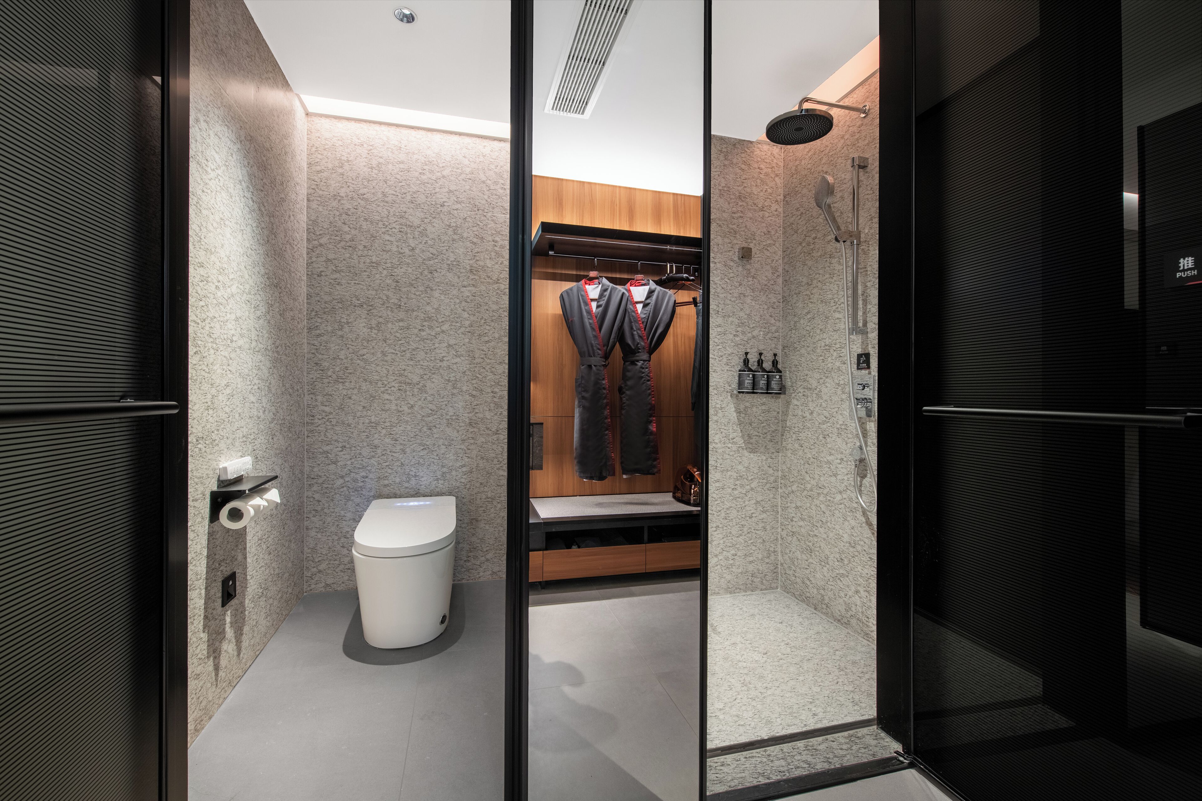 A modern bathroom with a toilet, shower, and a glass partition.