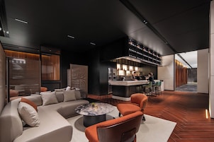 Un moderno vestíbulo de hotel con bar, zona de estar y vistas a la cocina.
