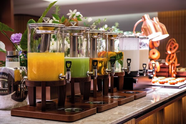 Un espace dédié aux boissons, équipé de plusieurs distributeurs, d’une machine à café et d’un présentoir à pâtisseries.
