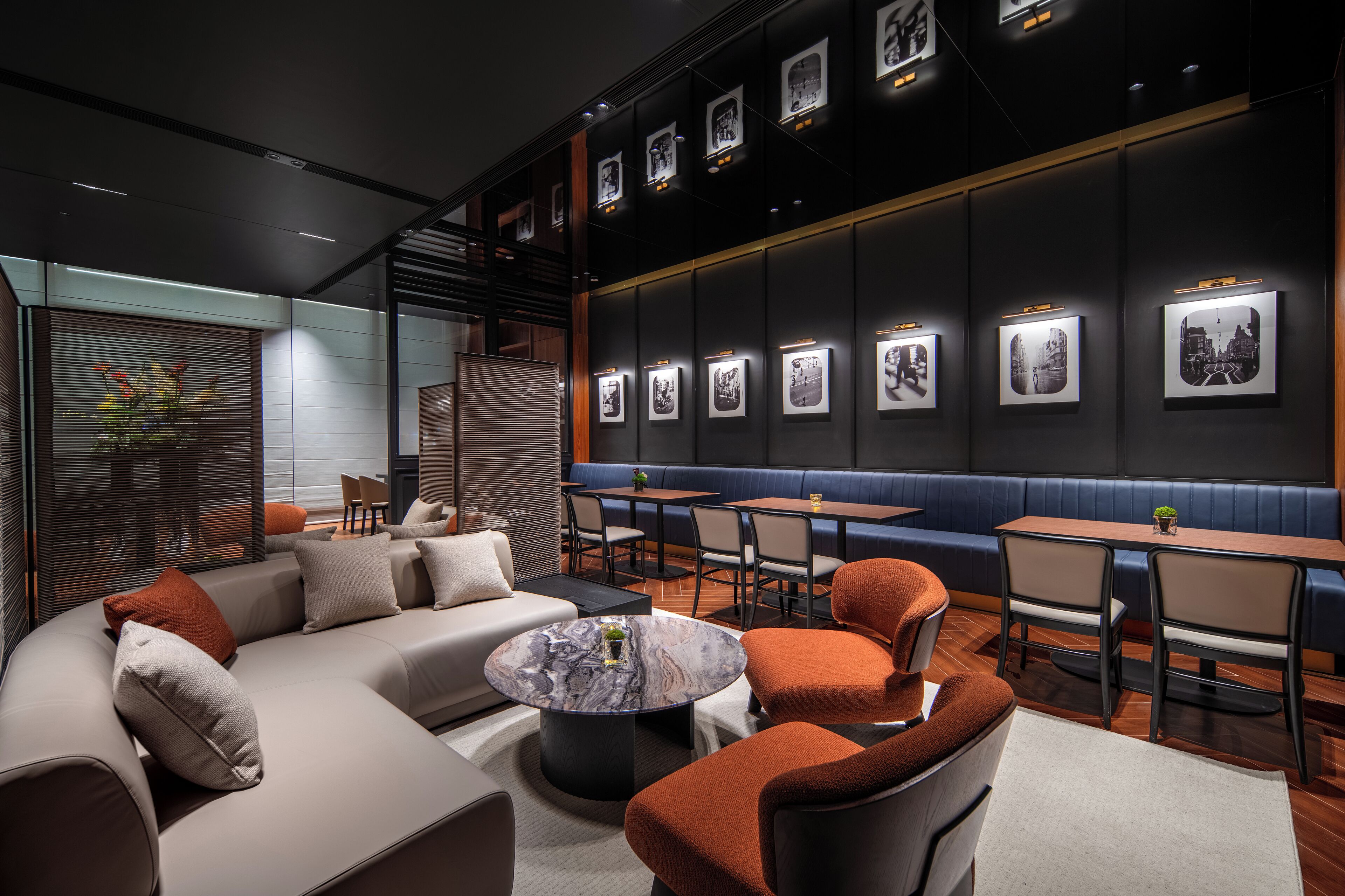 A modern lounge area with seating, tables, and wall-mounted artwork.